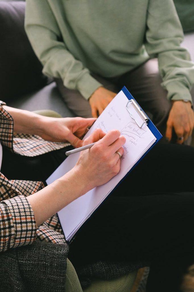woman-psychologist-taking-notes-on-clipboard-while-talking-with-client-7176291 Woman psychologist taking notes on clipboard while talking with client